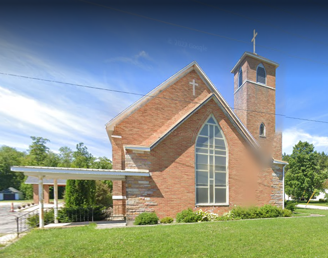 Brick church with large arched window and cross.