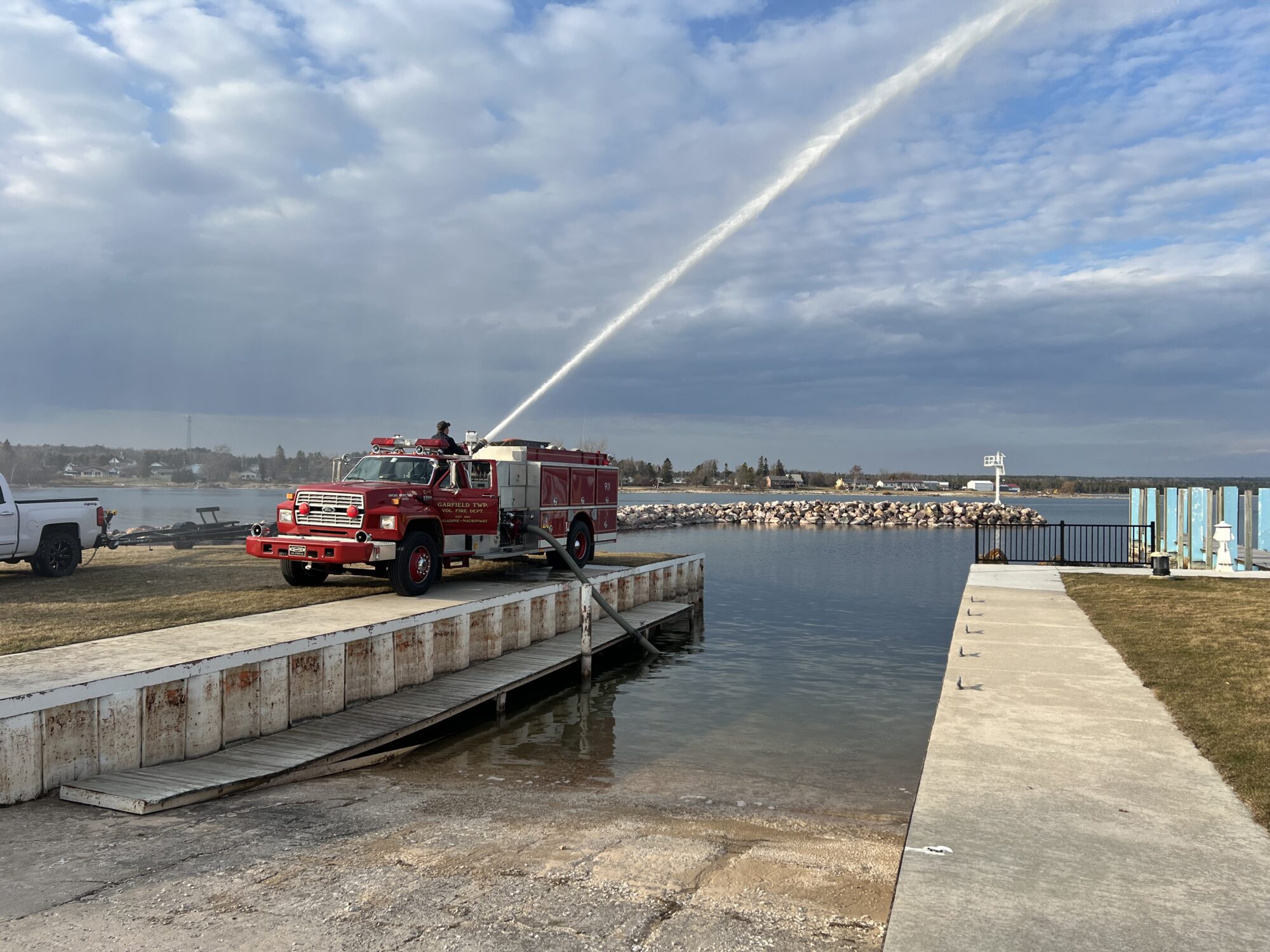 Fire truck spraying water at lakeside dock.