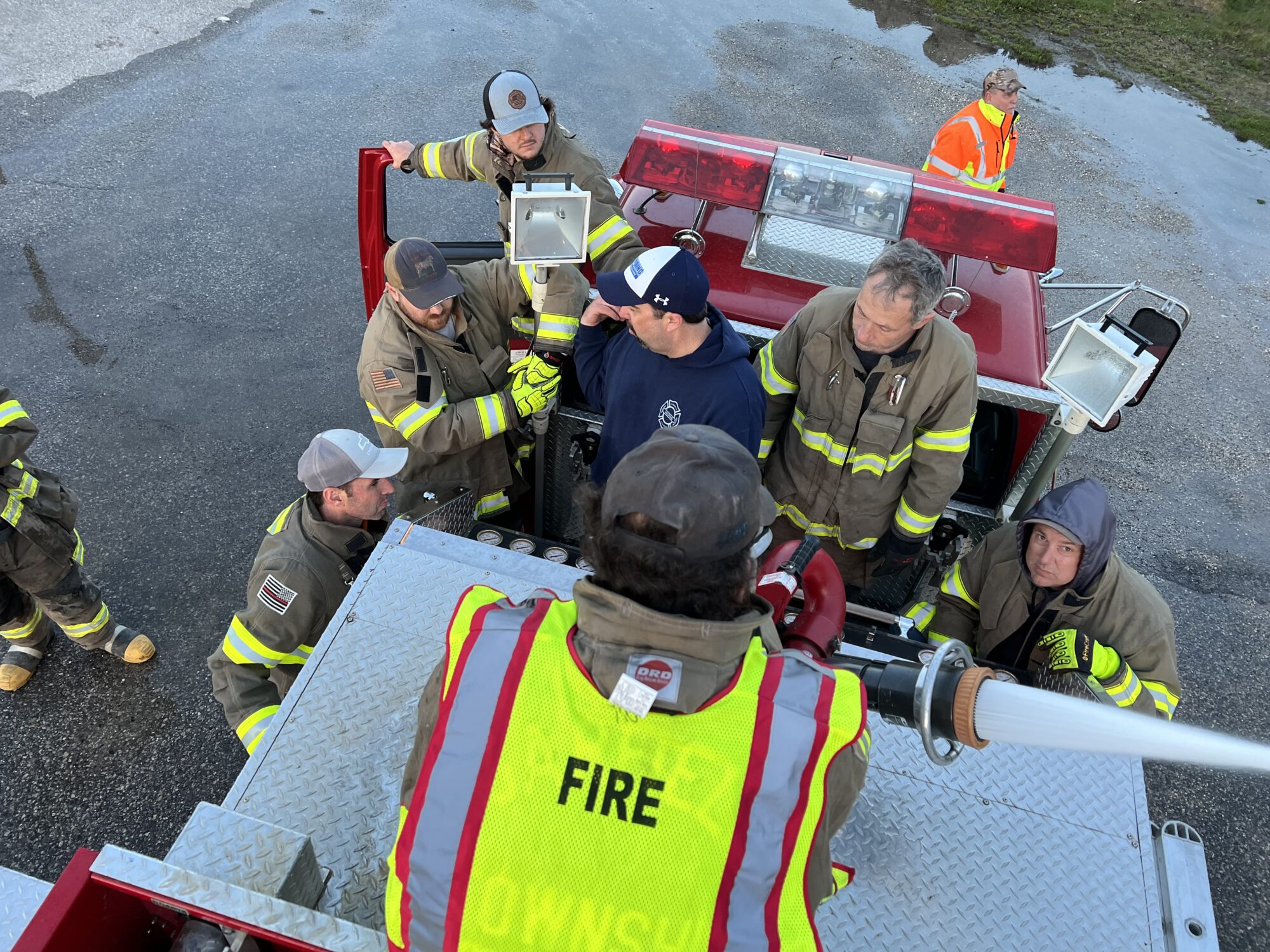 Firefighters training with fire truck equipment.