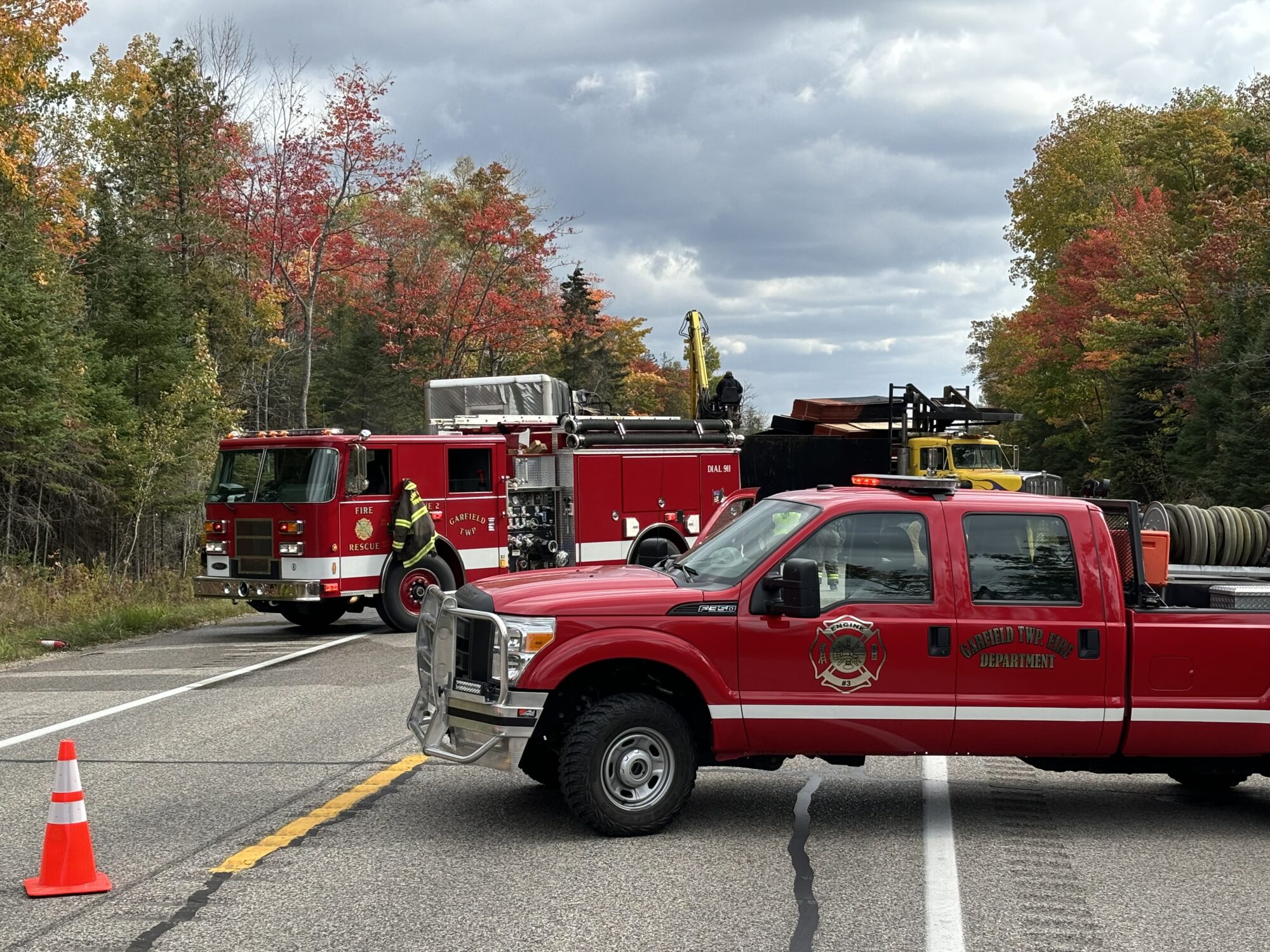 Fire trucks at scene with autumn trees background.