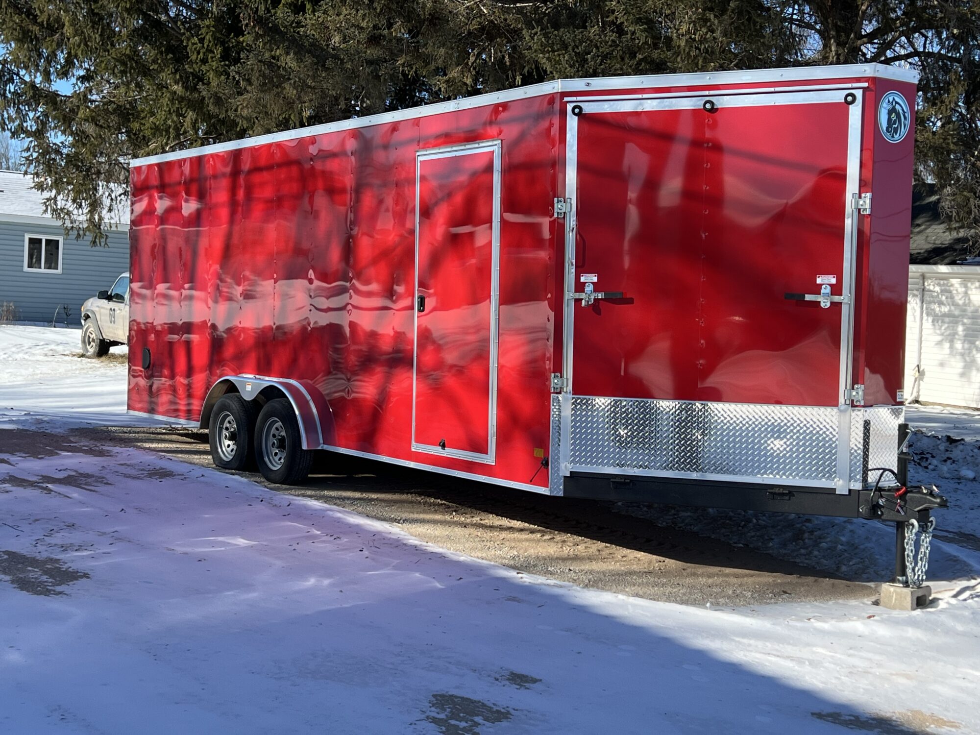 Red enclosed trailer parked on snowy pavement.