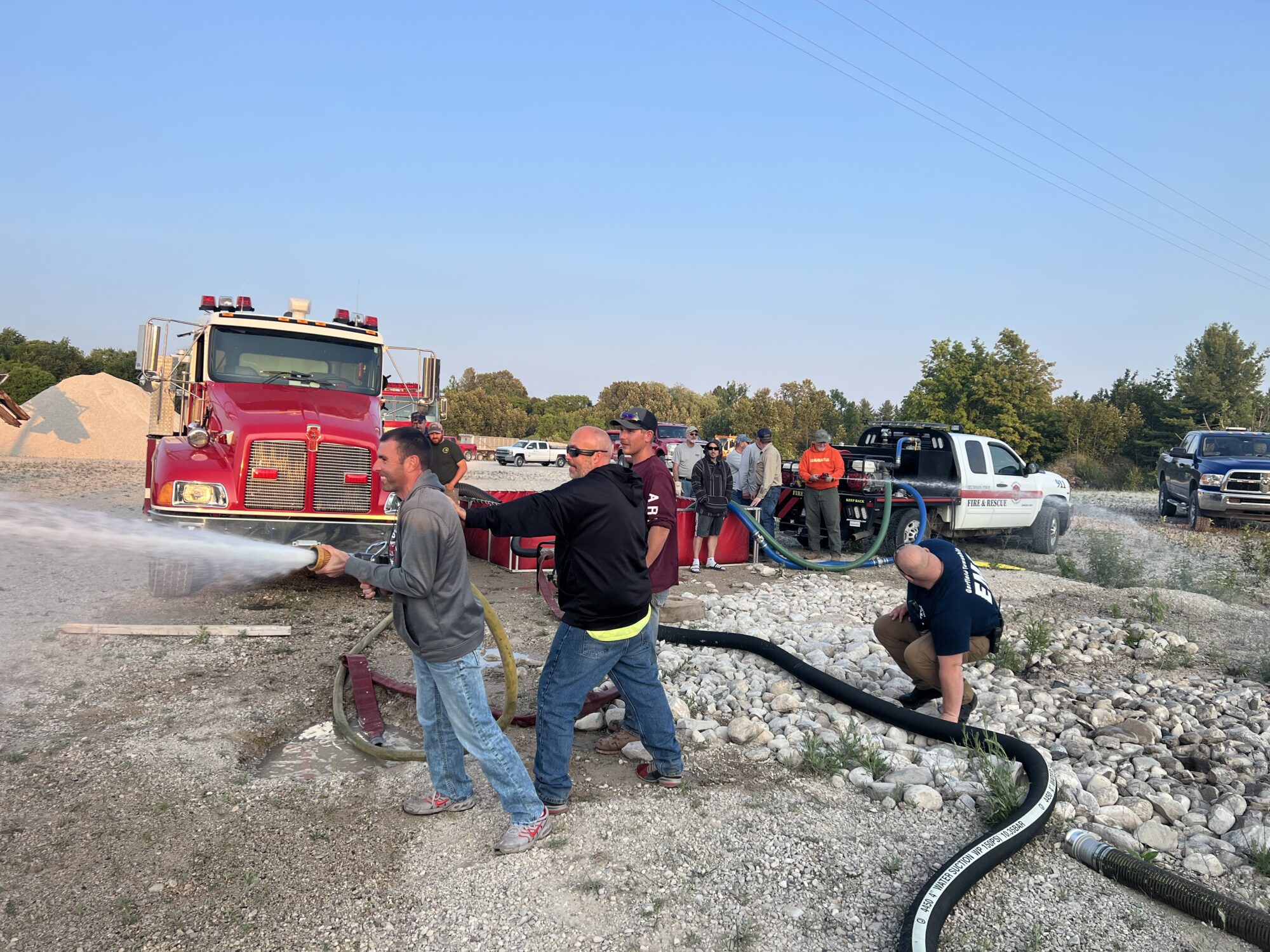 Firefighters operating hoses during training exercise outdoors.