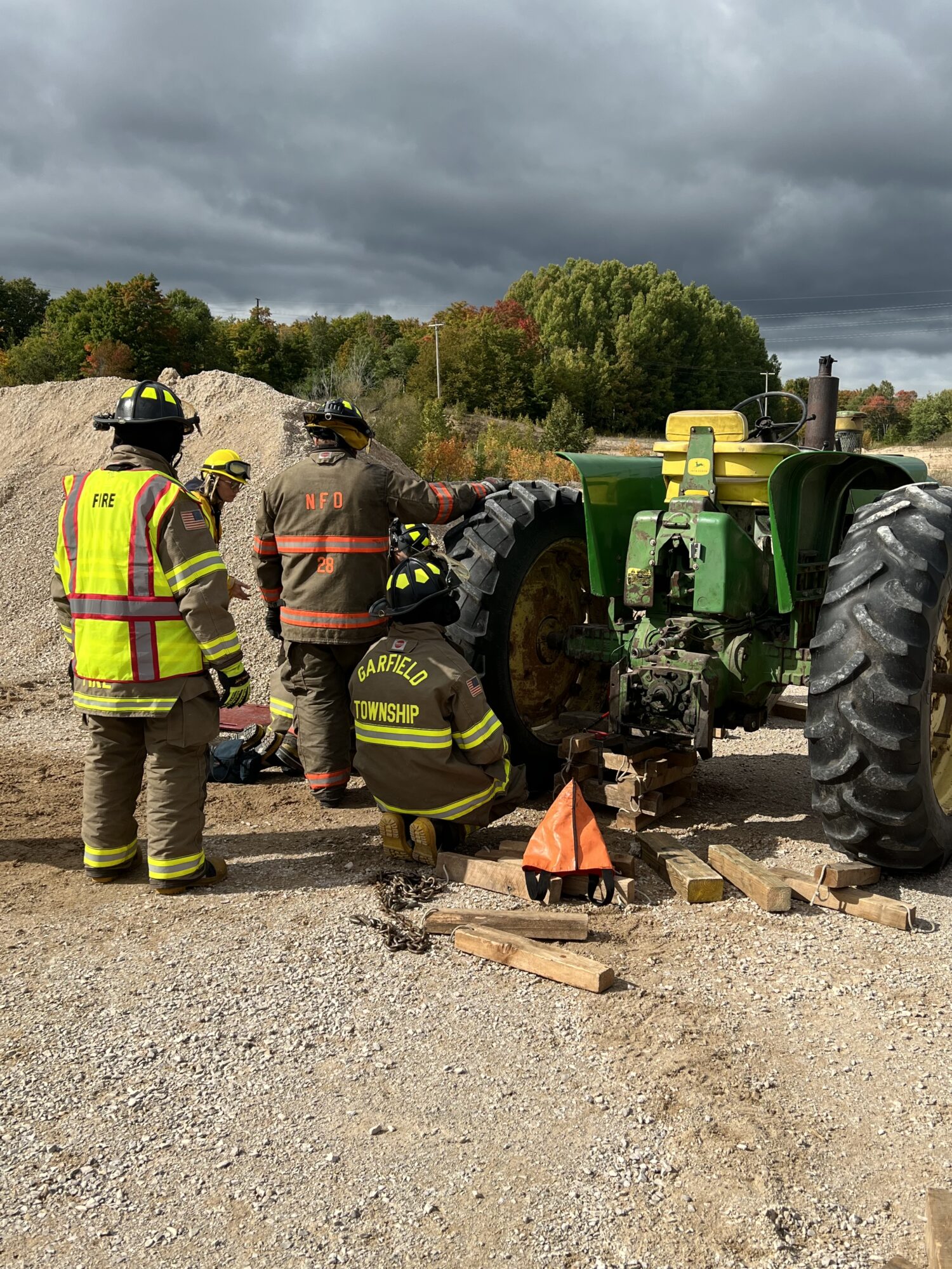 Firefighters inspecting tractor on gravel road.