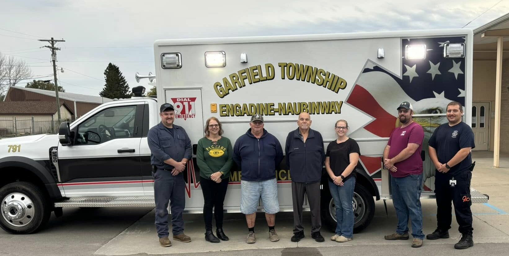 People standing in front of Garfield Township ambulance.