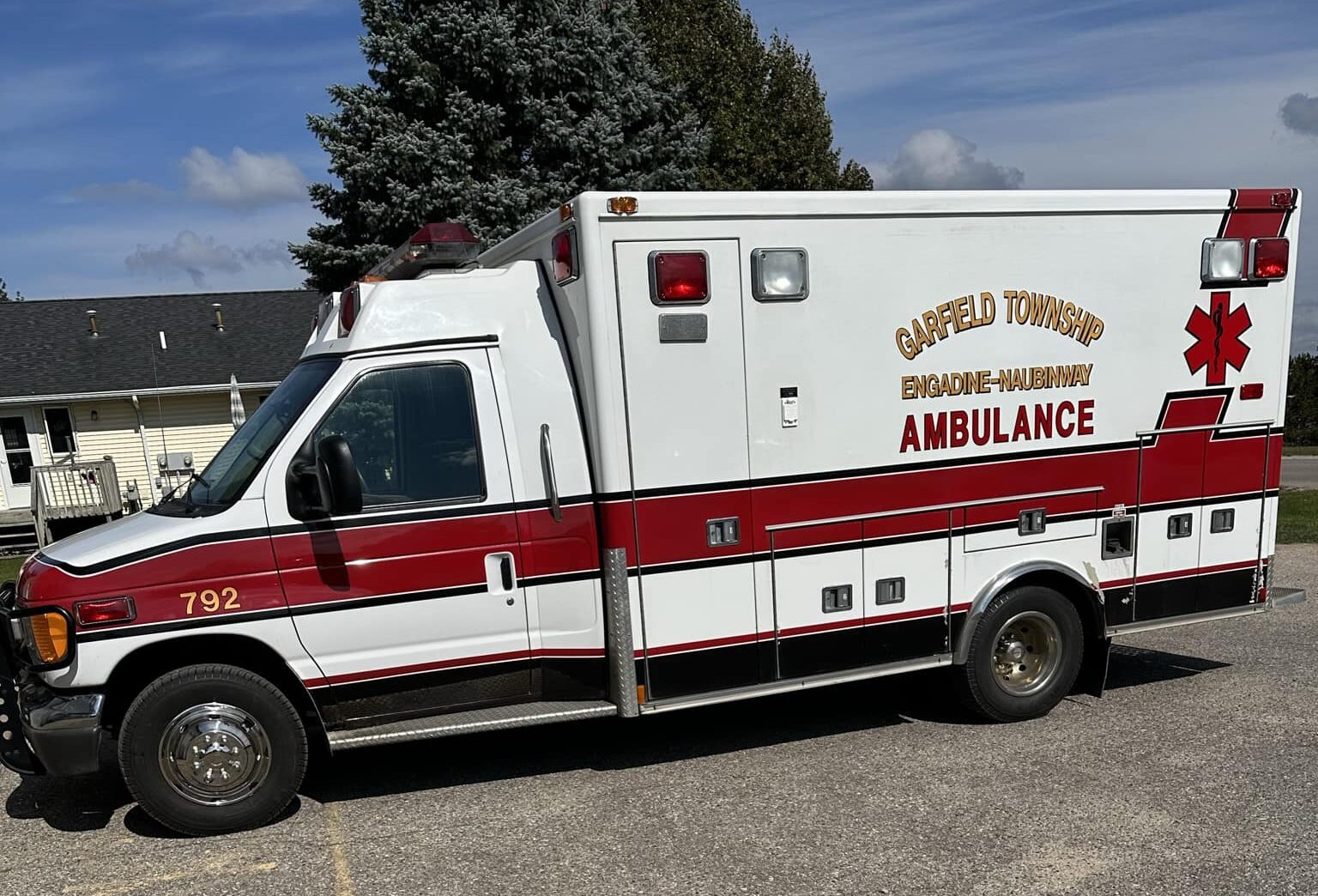 Red and white ambulance parked on a sunny day.